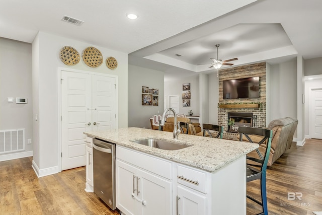 kitchen featuring a raised ceiling, a center island with sink, white cabinets, a kitchen breakfast bar, and sink