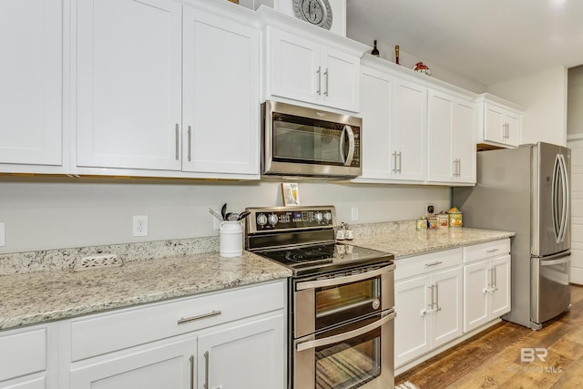 kitchen with stainless steel appliances, white cabinets, and hardwood / wood-style floors