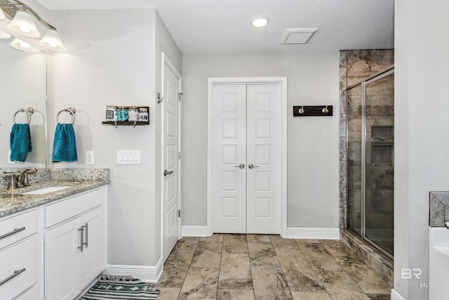 bathroom featuring a shower with door and vanity