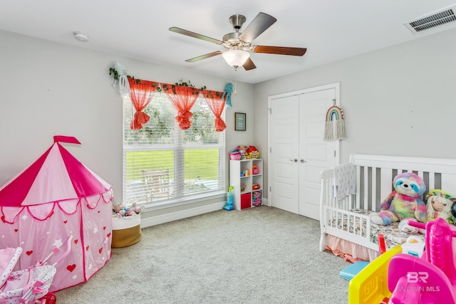 bedroom with ceiling fan, carpet floors, and a nursery area