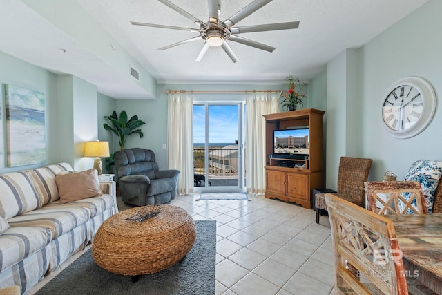 living room featuring ceiling fan, a textured ceiling, and light tile patterned flooring