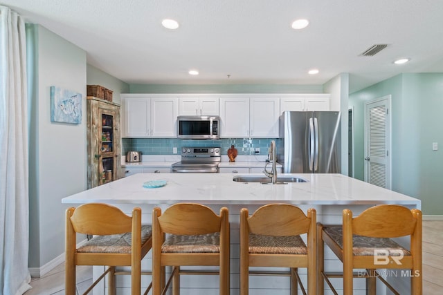 kitchen with appliances with stainless steel finishes, light tile patterned floors, sink, and tasteful backsplash