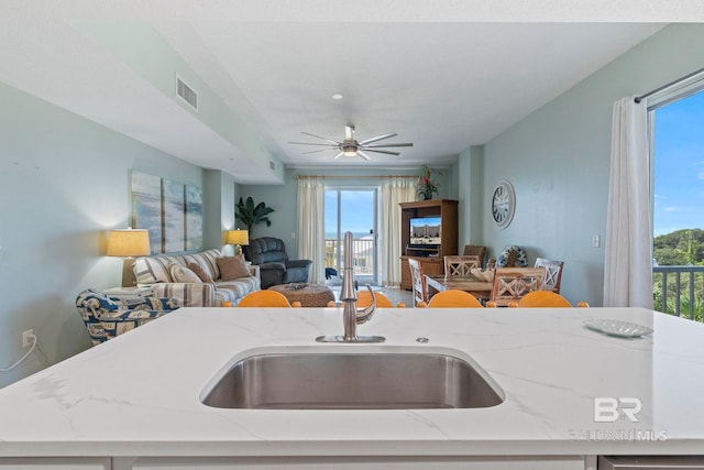 kitchen with ceiling fan, sink, plenty of natural light, and light stone counters