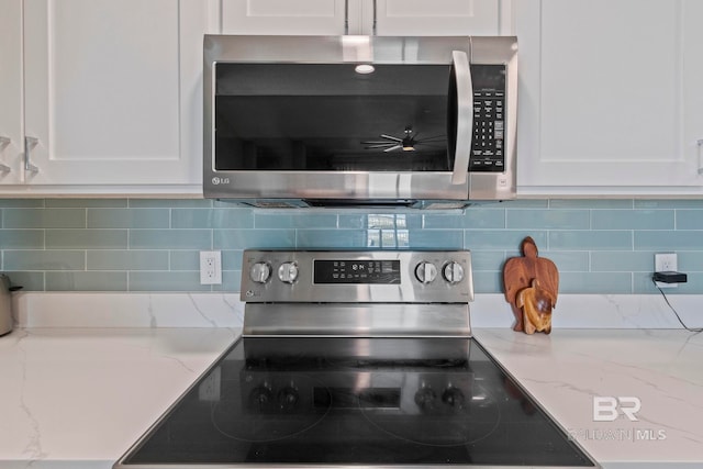 interior details featuring white cabinetry, appliances with stainless steel finishes, light stone counters, and backsplash