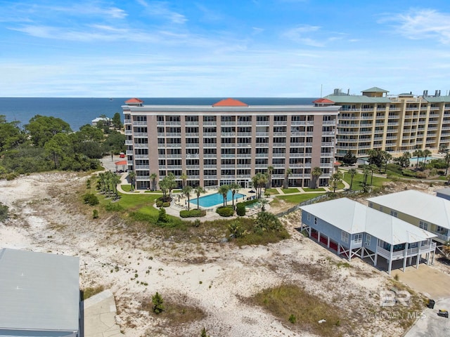 view of building exterior with a community pool and a water view