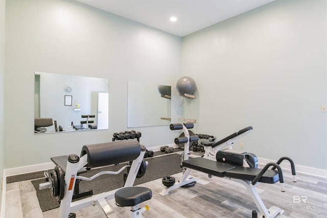 workout area with light hardwood / wood-style floors and a high ceiling