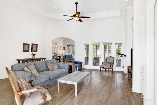 living room with hardwood / wood-style flooring, crown molding, a raised ceiling, and french doors