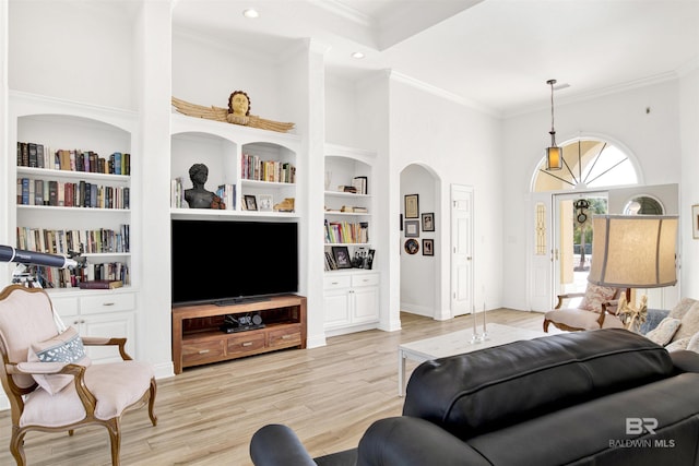 living room with ornamental molding, light hardwood / wood-style floors, and a high ceiling