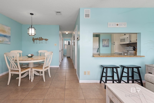 tiled dining space with sink and a textured ceiling