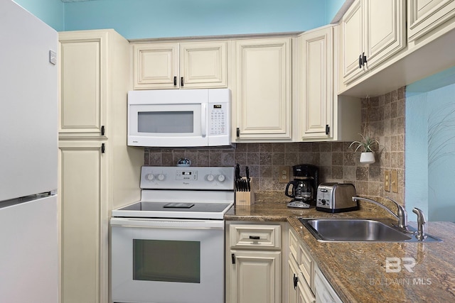 kitchen with sink, white appliances, backsplash, cream cabinets, and dark stone counters