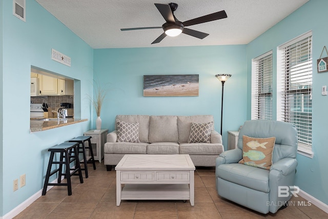 living room featuring ceiling fan, tile patterned floors, sink, and a textured ceiling