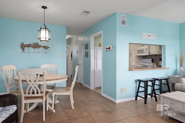 tiled dining area with a textured ceiling