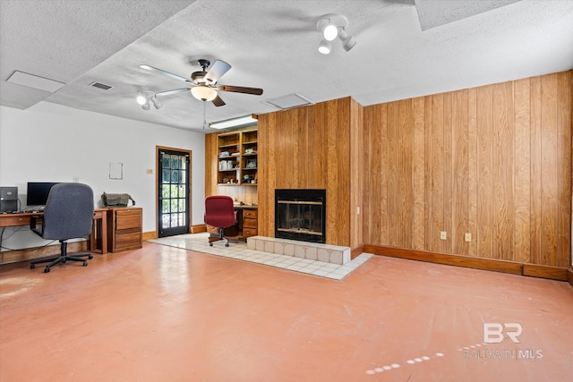 office area with ceiling fan, a textured ceiling, and wood walls