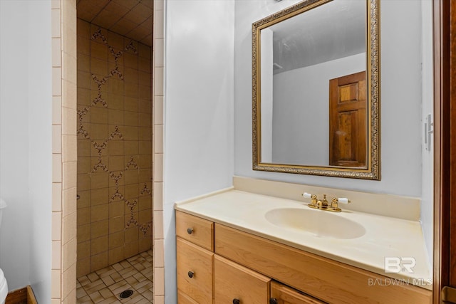 bathroom featuring vanity, tile patterned flooring, a tile shower, and toilet