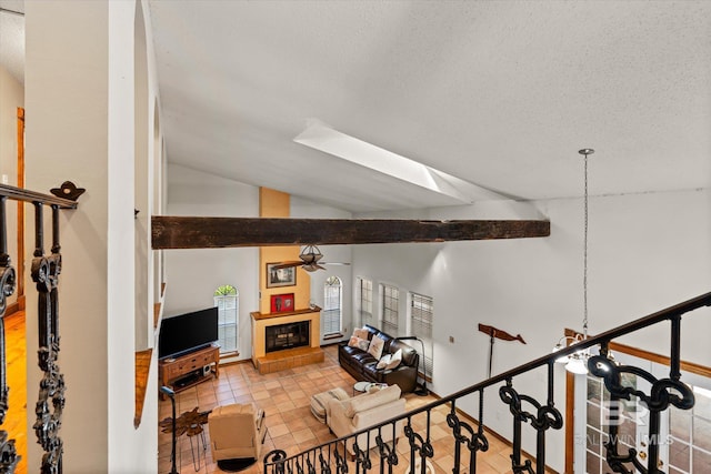 stairway with ceiling fan, a textured ceiling, lofted ceiling with skylight, and tile patterned floors