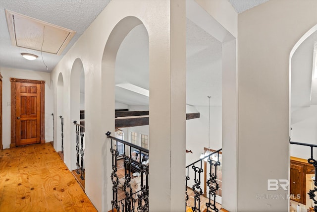 hallway with light wood-type flooring and a textured ceiling