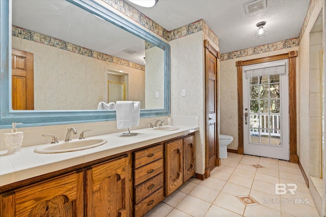 bathroom with tile patterned flooring, a textured ceiling, vanity, and toilet