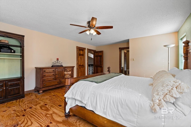 bedroom with a textured ceiling, hardwood / wood-style floors, and ceiling fan