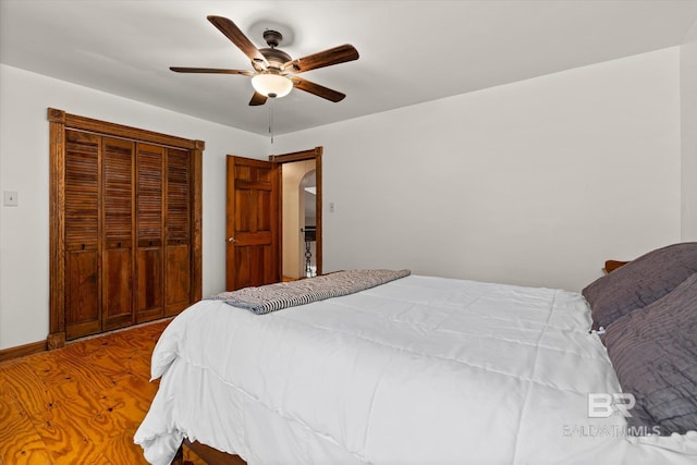 bedroom with ceiling fan, a closet, and wood-type flooring