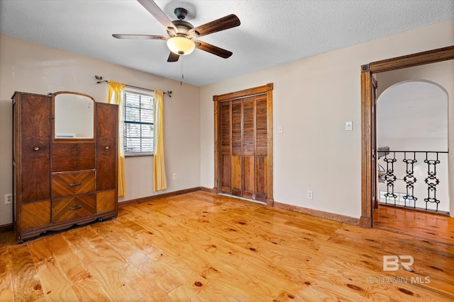 unfurnished bedroom with ceiling fan, a textured ceiling, and light wood-type flooring