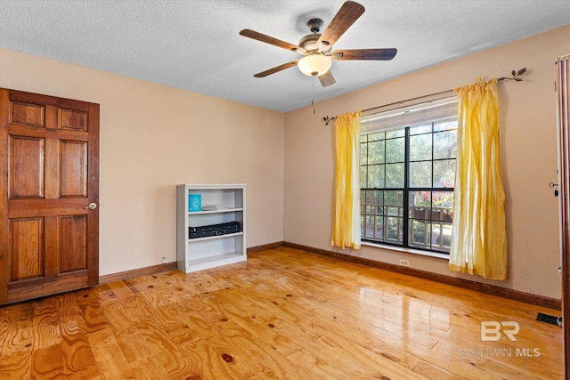 interior space featuring light wood-type flooring, a textured ceiling, and ceiling fan