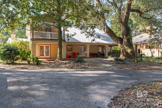 view of front of property with french doors, a balcony, and covered porch