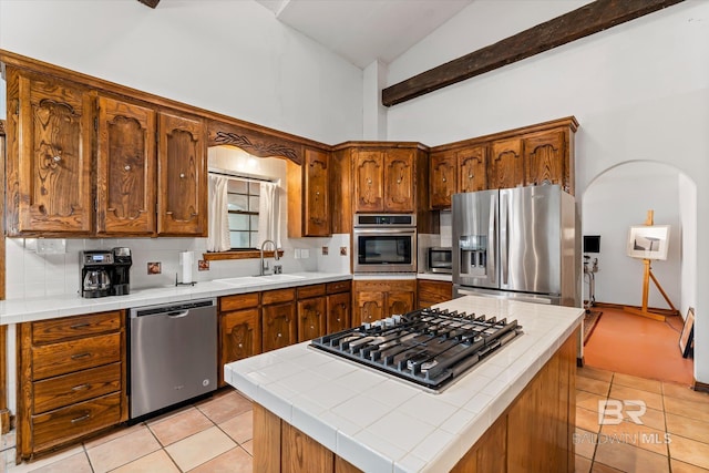 kitchen featuring sink, a kitchen island, stainless steel appliances, tile countertops, and light tile patterned floors