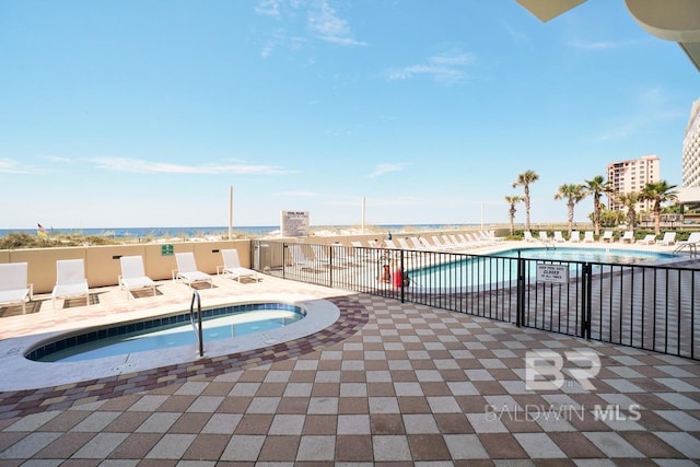 view of swimming pool featuring a water view, a patio, and a hot tub