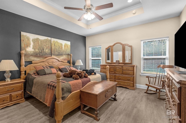 bedroom with a tray ceiling, crown molding, ceiling fan, and light hardwood / wood-style flooring