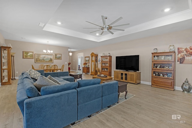 living room featuring a raised ceiling, light hardwood / wood-style flooring, ceiling fan with notable chandelier, and ornamental molding