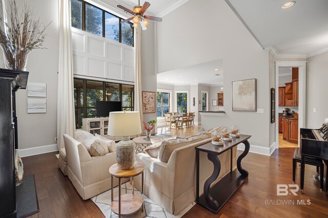 living room featuring ornamental molding, a high ceiling, a healthy amount of sunlight, and dark hardwood / wood-style flooring