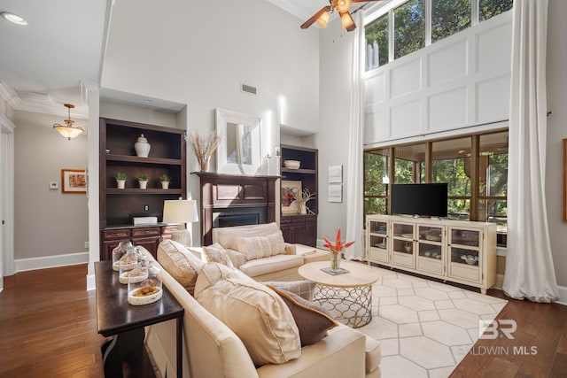 living room with a towering ceiling, crown molding, dark hardwood / wood-style floors, and ceiling fan