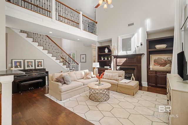 living room with a high ceiling, ornate columns, hardwood / wood-style flooring, and ceiling fan