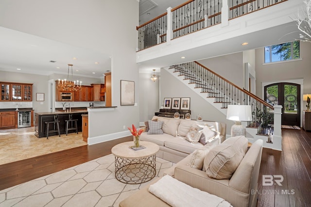 living room featuring wine cooler, crown molding, wood-type flooring, and a towering ceiling