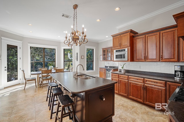 kitchen featuring tasteful backsplash, sink, an island with sink, stainless steel oven, and crown molding