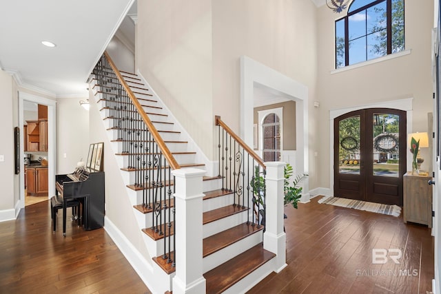 entrance foyer with french doors, crown molding, a towering ceiling, and dark hardwood / wood-style flooring