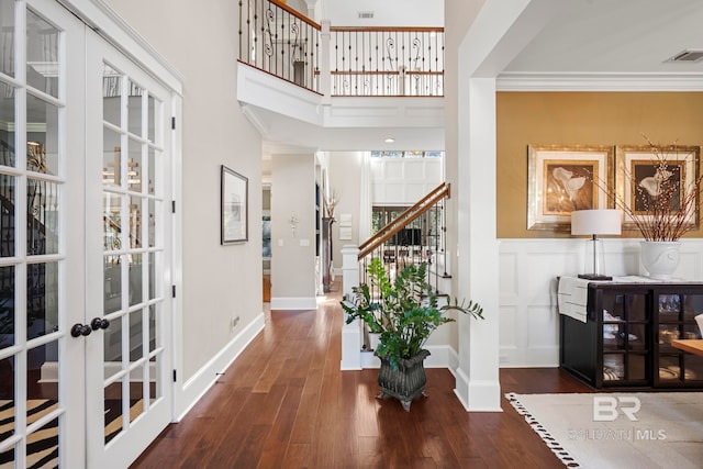 foyer featuring ornamental molding, french doors, dark hardwood / wood-style floors, and a towering ceiling