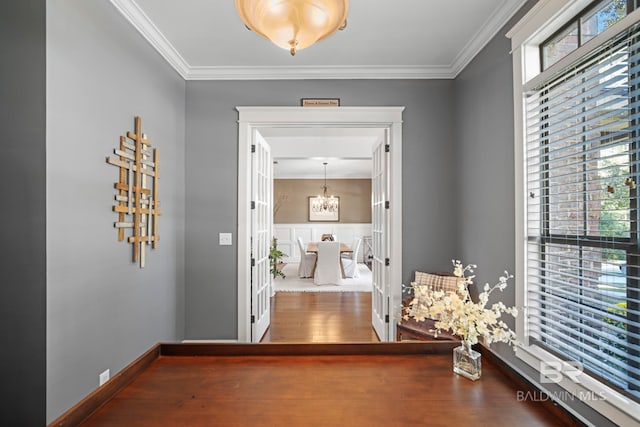 hall featuring a notable chandelier, ornamental molding, and wood-type flooring