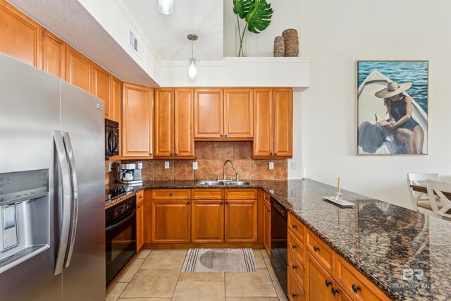 kitchen with sink, black appliances, pendant lighting, dark stone countertops, and light tile patterned flooring