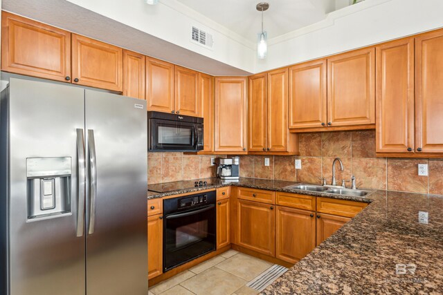 kitchen with sink, hanging light fixtures, dark stone counters, light tile patterned floors, and black appliances