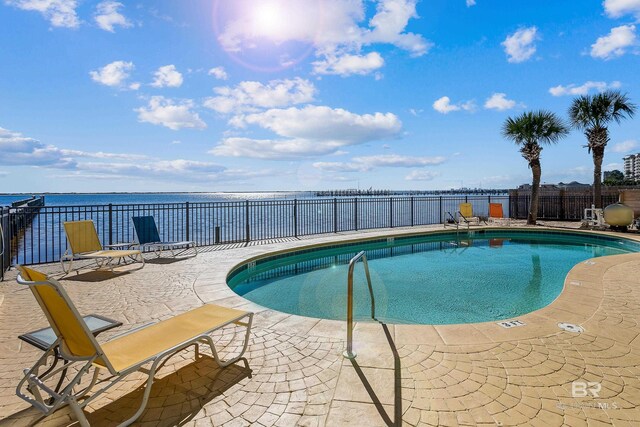 view of pool with a water view and a patio