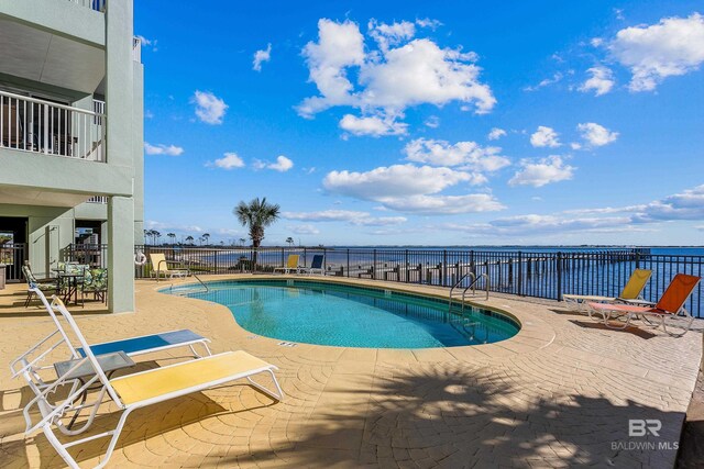 view of swimming pool featuring a patio area and a water view