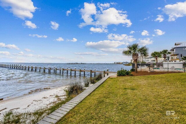 view of dock featuring a lawn and a water view