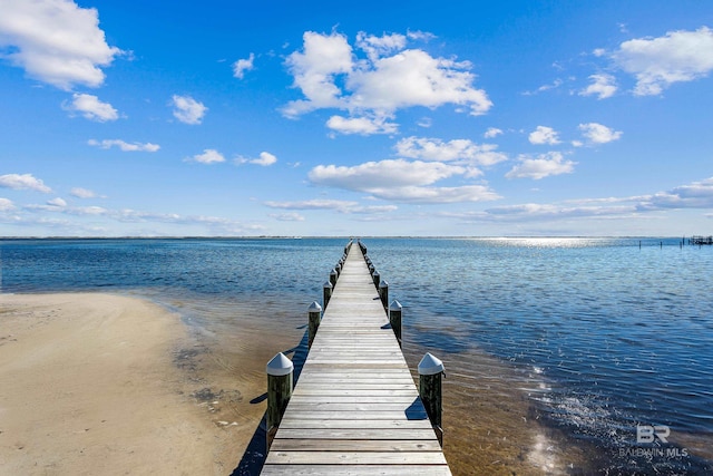 view of dock featuring a water view and a beach view