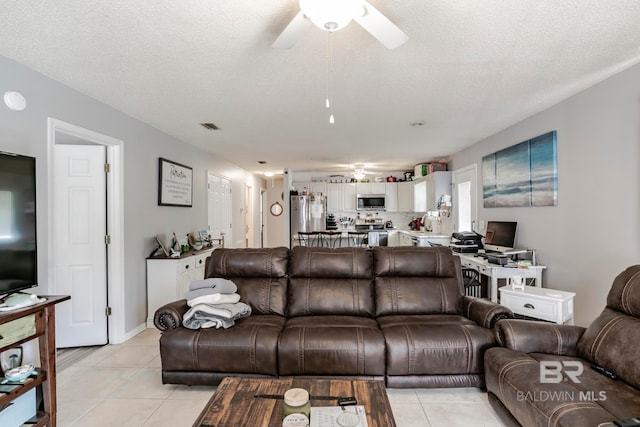 living room with ceiling fan, a textured ceiling, and light tile patterned floors