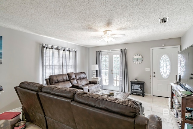 tiled living room with ceiling fan, a textured ceiling, and french doors