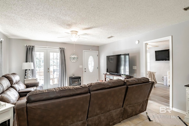 living room featuring ceiling fan, a textured ceiling, light tile patterned floors, and french doors