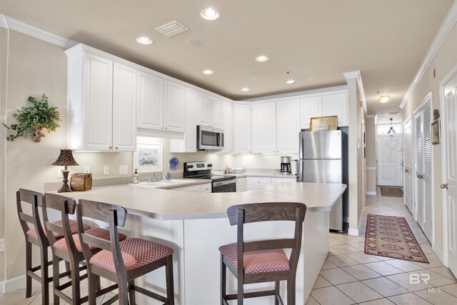 kitchen with ornamental molding, appliances with stainless steel finishes, light tile patterned flooring, and white cabinets