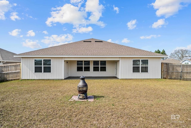 back of house with a fire pit and a lawn