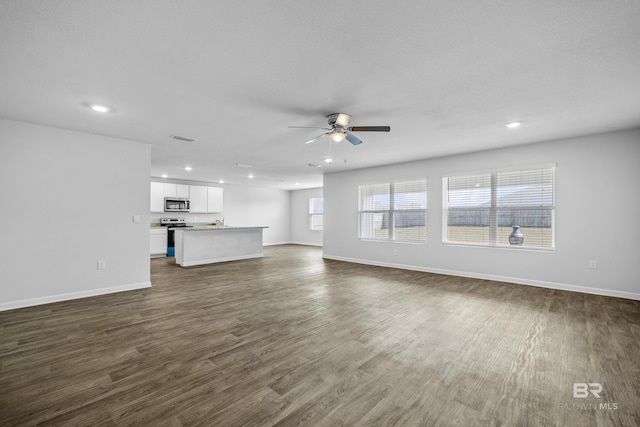 unfurnished living room with dark hardwood / wood-style flooring and ceiling fan